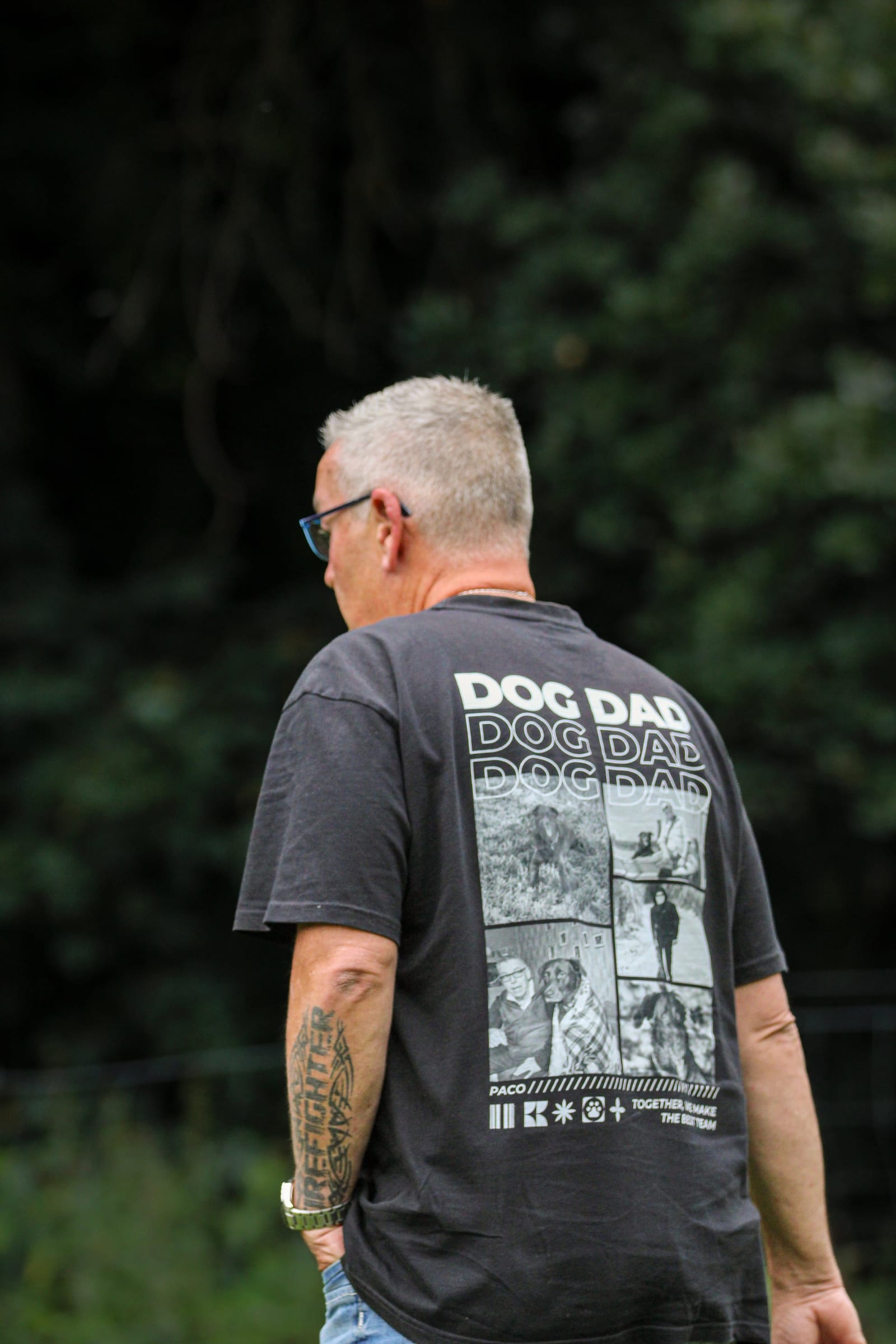 Hundebesitzer von hinten im Grünen, auf seinem T-Shirt steht Dog Dad