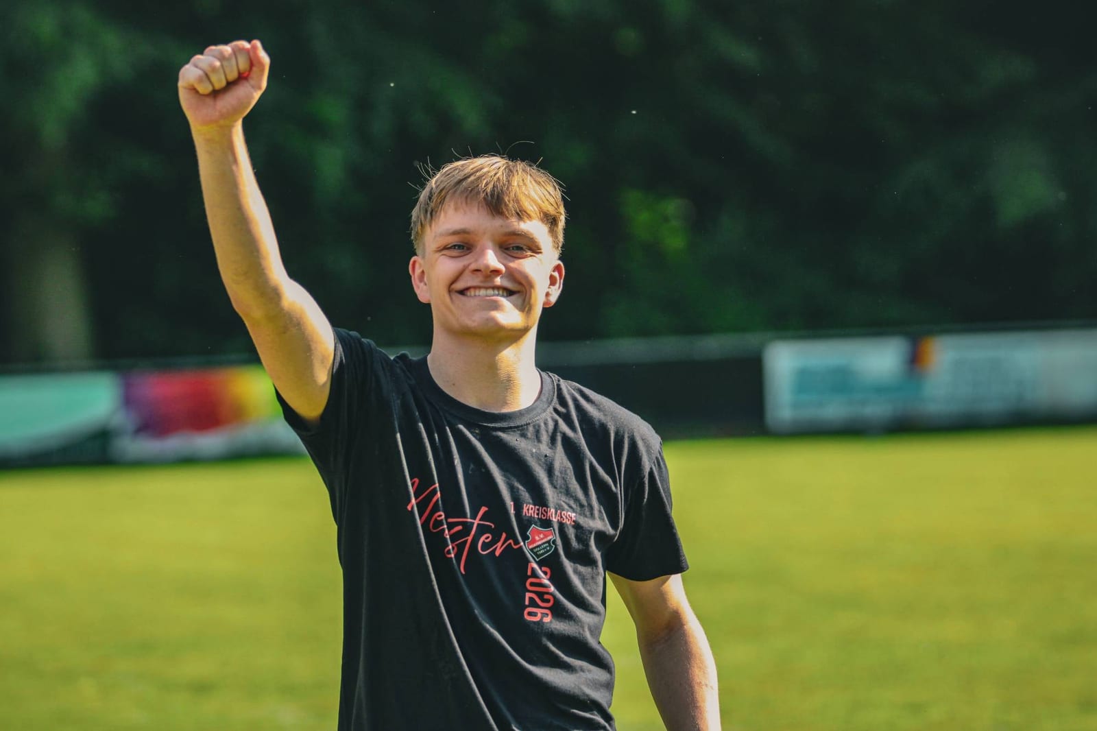 Junger Spieler im Meister-Shirt reckt lachend die Faust in die Luft