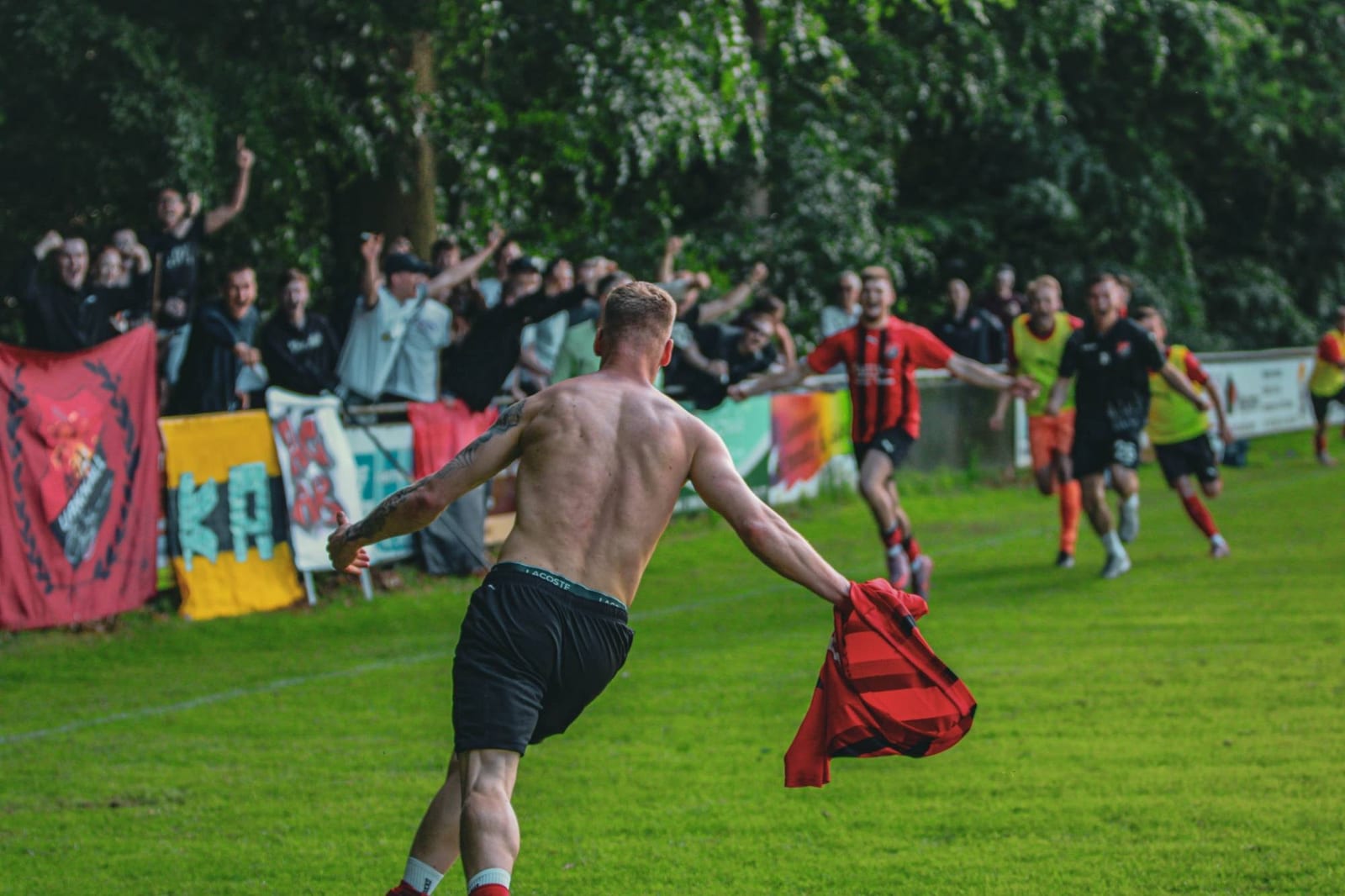 Ein Spieler läuft mit dem Trikot in der Hand zu den jubelnden Fans hinter der Bande