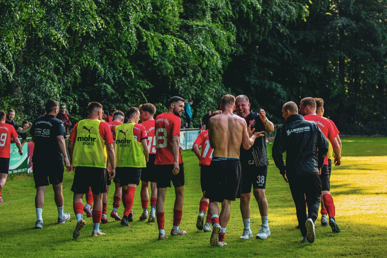 Die Mannschaft geht nach dem Spiel gemeinsam über den Platz, das Licht fällt gelb auf den Rasen