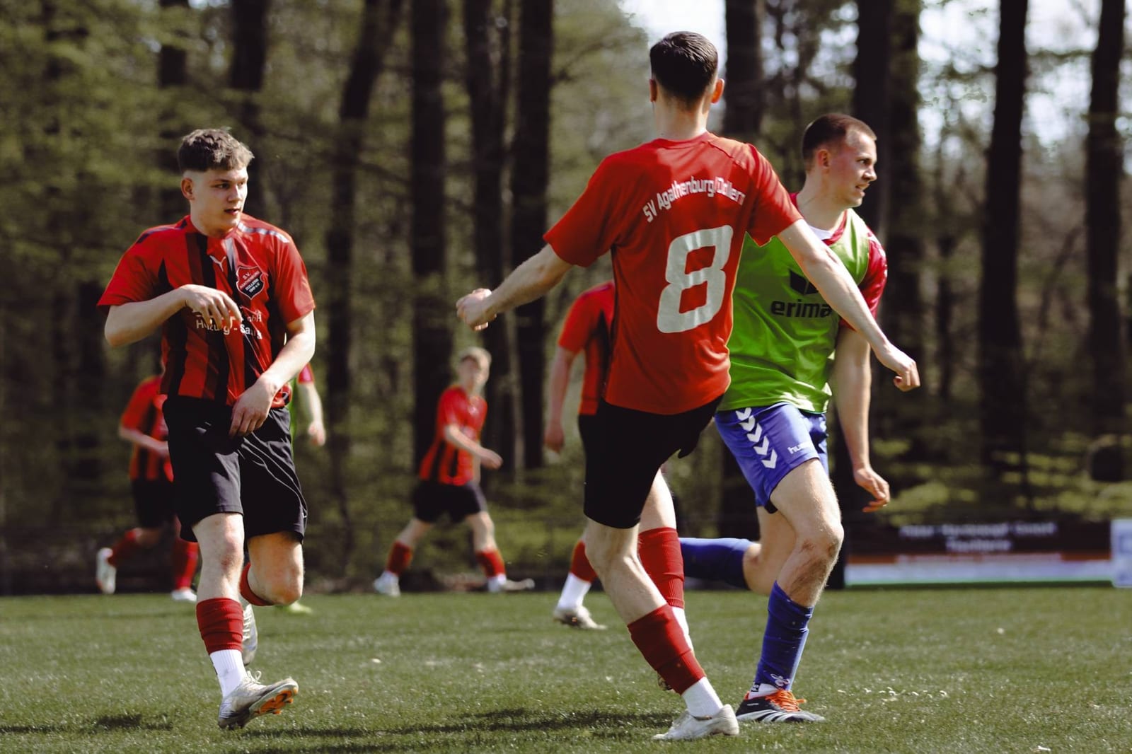 Spieler mit der Nummer 8 läuft zwischen Gegenspielern Richtung Ball