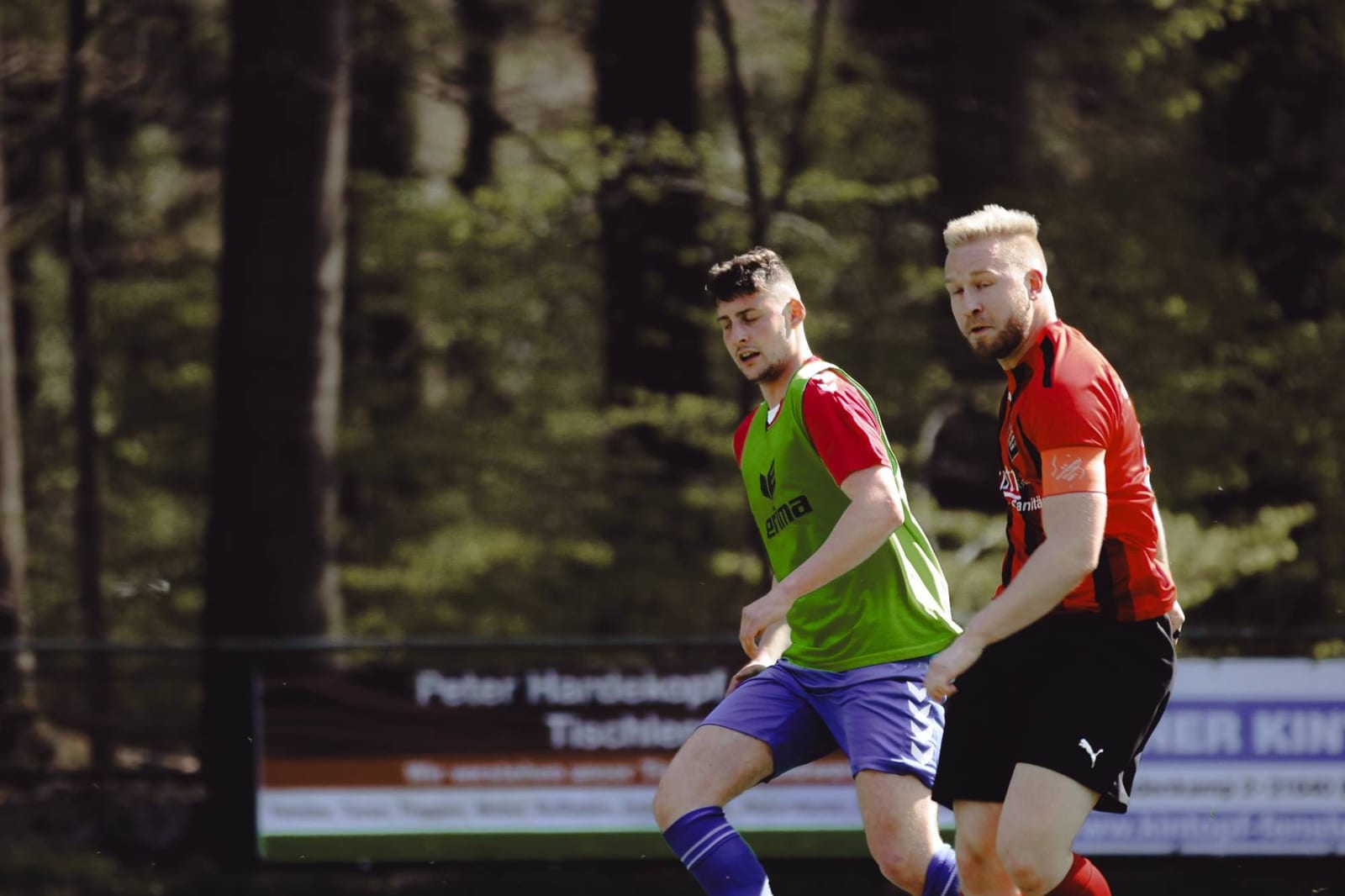 Zwei Spieler laufen Schulter an Schulter dem Ball entgegen
