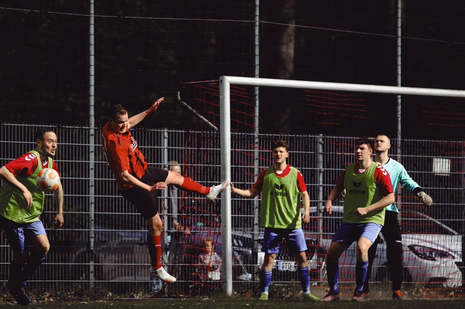 Ein Spieler springt im Strafraum hoch zum Ball, vor dem Tor warten Gegenspieler und Torwart