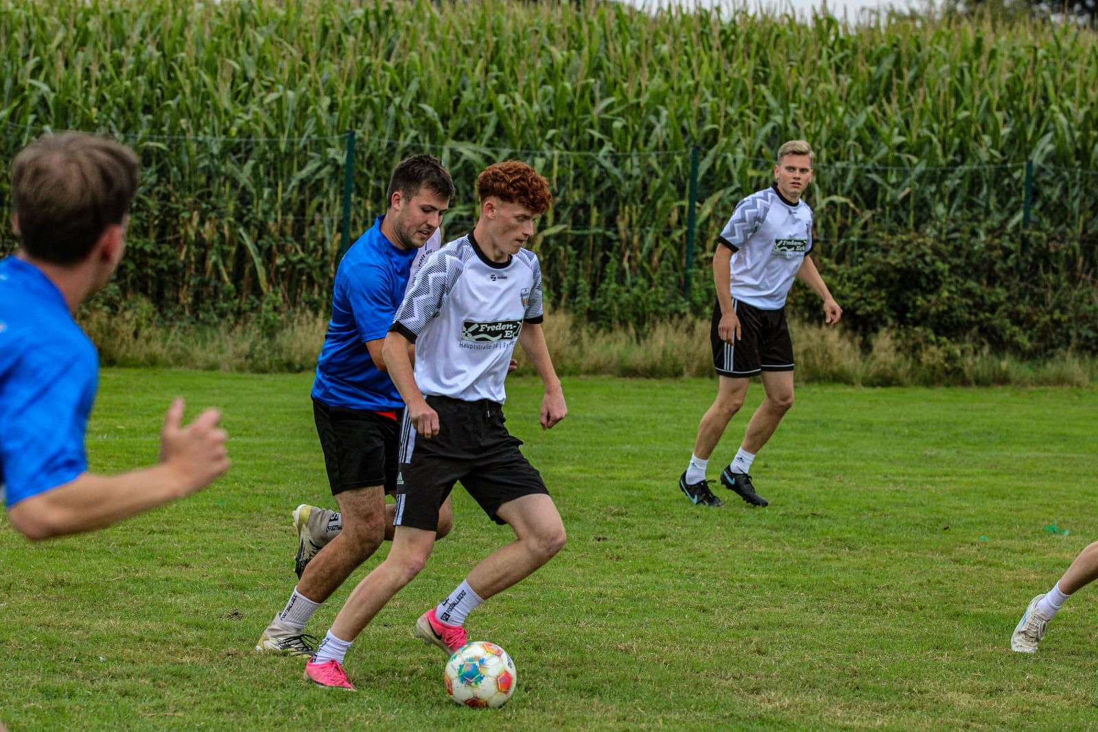 Spieler in Weiß und Blau laufen beim Turnier gemeinsam dem Ball hinterher