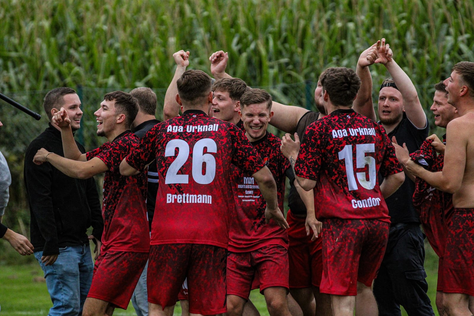 Spieler mit den Nummern 26 und 15 jubeln mit erhobenen Armen nach dem Abpfiff