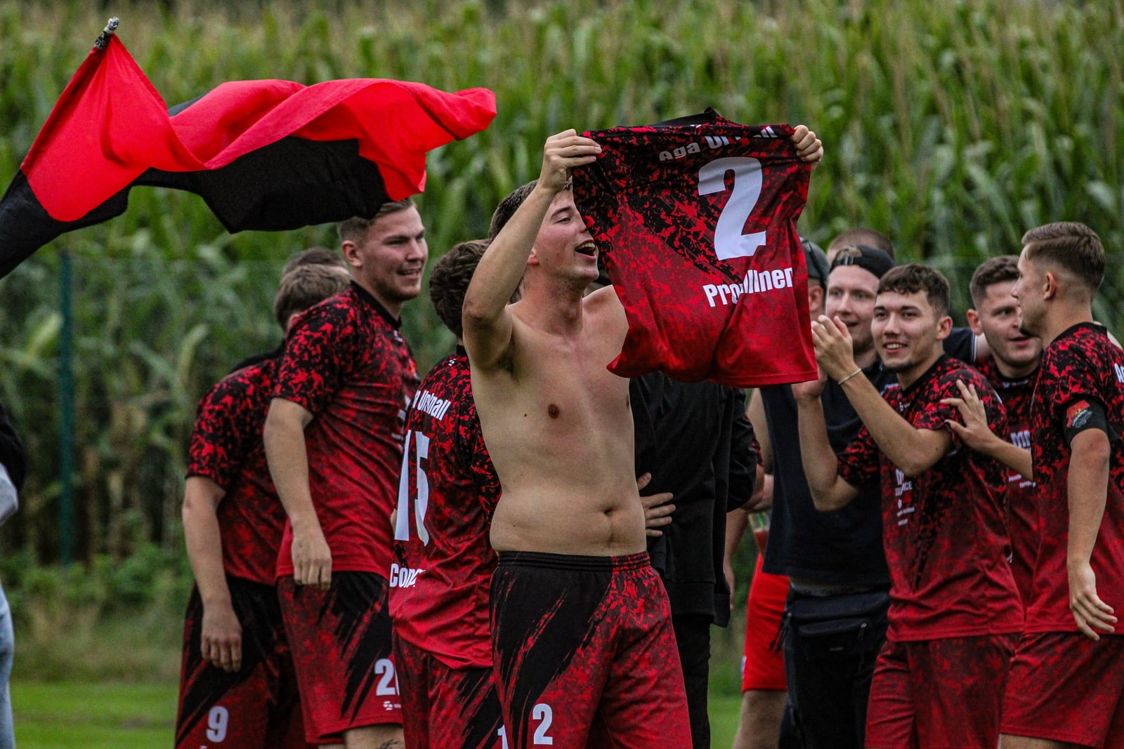 Nach dem Finale hält ein Spieler jubelnd sein Trikot mit der Nummer 2 in die Höhe, um ihn feiert die Mannschaft