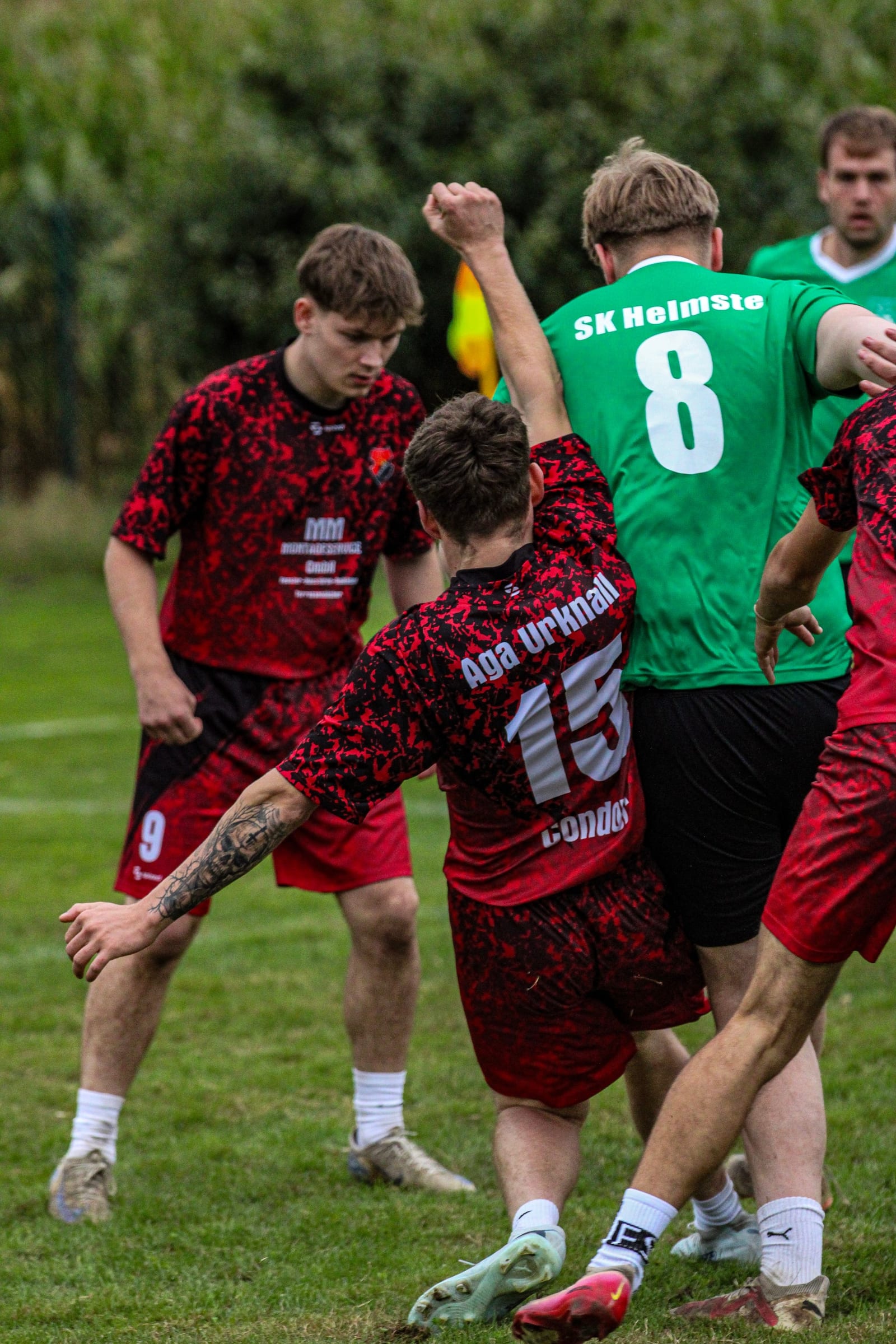 Spieler mit der Nummer 15 im roten Trikot kämpft gegen einen Gegner im grünen Trikot um den Ball